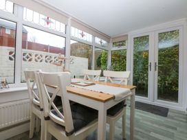 A conservatory with a dining table and chairs at Pebbles Reach in Colwyn Bay