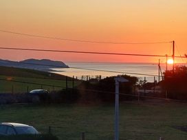 A sunset over the ocean with hills and power lines at Pebbles Reach in Llysfaen