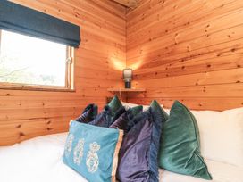 A bed with multiple pillows next to a window and wooden walls at Shepherd's Hut in Scarborough