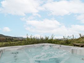 A hot tub with water and bubbles outdoors with plants hills and sky in the background at Shepherd's Hut in Scarborough