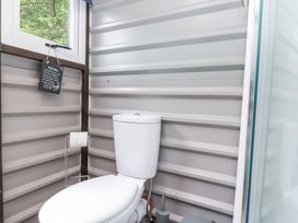 A bathroom with a white toilet next to a window and a shower at Shepherd's Hut in Scarborough