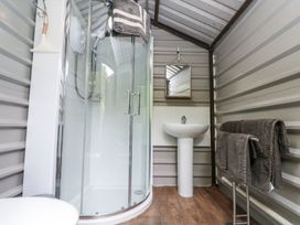 A bathroom with a glass shower enclosure a pedestal sink a mirror and towels on a rack at Shepherd's Hut in Scarborough