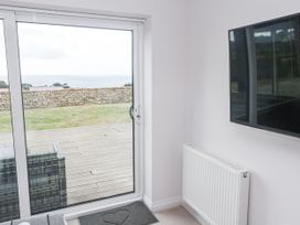 A living room with a sliding door and television at Atlantic View in Germoe