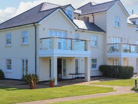 External view of a cream colored residential building with balconies and glass railings on a lawn at 4 Thurlestone Beach House South Milton near Thurlestone