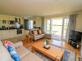 A living room with sofas cushions coffee table and a kitchen in the background at 4 Thurlestone Beach House in South Milton near Thurlestone