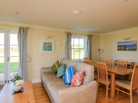 A living room with a sofa with colorful cushions a wooden dining table with chairs and a window at 4 Thurlestone Beach House in South Milton near Thurlestone