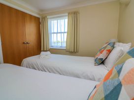 A bedroom with two single beds a window with curtains and a wooden closet at 4 Thurlestone Beach House South Milton near Thurlestone