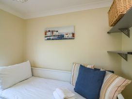A bedroom corner with a white bed and pillows a painting on the wall and shelves with a wicker basket at 4 Thurlestone Beach House South Milton near Thurlestone