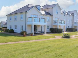 A white multi-unit residential building with balconies and a grassy lawn at 4 Thurlestone Beach House South Milton near Thurlestone