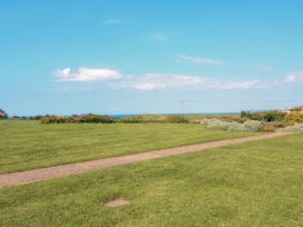 A grassy field with a narrow path and bushes under a blue sky at 4 Thurlestone Beach House South Milton near Thurlestone