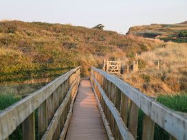A wooden footbridge leading to a gate surrounded by grassy hills at 4 Thurlestone Beach House in South Milton near Thurlestone