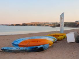 Kayaks stacked on a sandy beach near calm water with cliffs and buildings in the background at 4 Thurlestone Beach House South Milton near Thurlestone