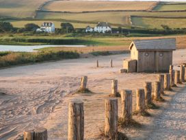 A sandy area with wooden posts and a small wooden hut near a body of water and fields in the background at 4 Thurlestone Beach House South Milton near Thurlestone