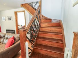 A staircase leading to the upper floor with a sofa in the living room at Chapel Cottage in Sandford, Cumbria