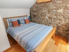 A bedroom with a bed and stone wall at Chapel Cottage in Sandford, Cumbria