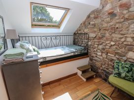 A bedroom with a bed and a green chair at Chapel Cottage in Sandford, Cumbria