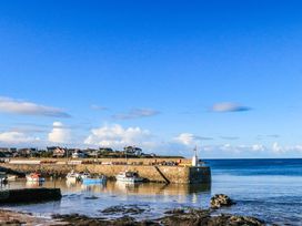 A harbor with boats docked near a stone pier and houses in the background at Monfa in Cemaes Bay