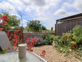 A garden with flowers and a table with a cup at Tiny Willow in Farrington near Child Okeford