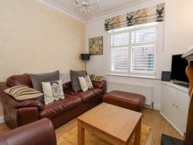 A living room with a brown leather sofa ottoman wooden coffee table window blinds radiator and a television at 202 Salisbury Terrace in York