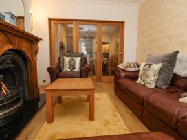 A living room with leather sofas a wooden coffee table a fireplace and glass doors leading to a dining room at 202 Salisbury Terrace in York