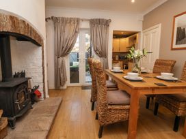 A dining area with wicker chairs around a wooden table and a wood stove next to double glass doors at 202 Salisbury Terrace in York