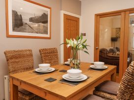 A dining room with a wooden table set for four and a vase of white flowers at 202 Salisbury Terrace in York