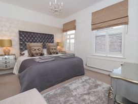A bedroom with a double bed with Buddha face pillows bedside tables lamps and windows with blinds at 202 Salisbury Terrace in York