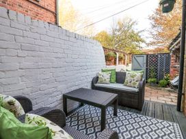 An outdoor patio area with dark wicker furniture a patterned rug and a white painted brick wall at 202 Salisbury Terrace in York