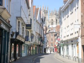 A narrow street lined with shops and historic buildings with a cathedral in the background in York