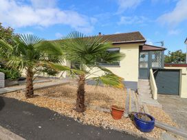 An outdoor area with palm trees and gravel at Daisy Cottage in Benllech
