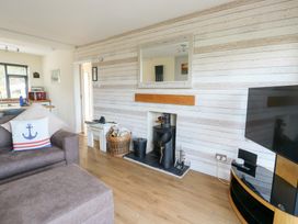 A living room with a sofa, television and fireplace at Daisy Cottage in Benllech