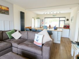 A living room with a sofa and dining area at Daisy Cottage in Benllech