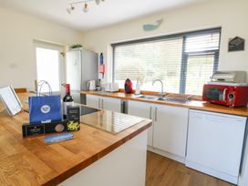 A kitchen with a sink, refrigerator, and various appliances at Daisy Cottage in Benllech