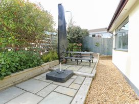 A garden with a table, benches, and a parasol at Daisy Cottage in Benllech
