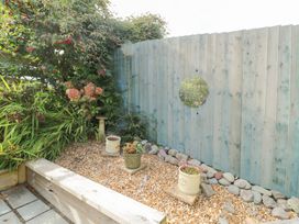A garden with flower pots and a gravel area at Daisy Cottage Benllech