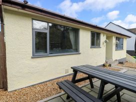 An outdoor seating area with a table next to a house at Daisy Cottage Benllech