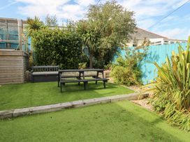 A garden with grass, a table, and plants at Daisy Cottage in Benllech