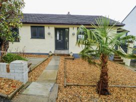 A house with a front door and palm tree at Daisy Cottage in Benllech