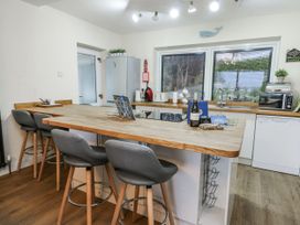 A kitchen with stools and a counter at Daisy Cottage in Benllech