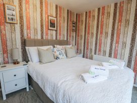 A bedroom with a bed and bedside tables at Daisy Cottage in Benllech