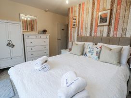 A bedroom with a bed and wardrobe at Daisy Cottage in Benllech