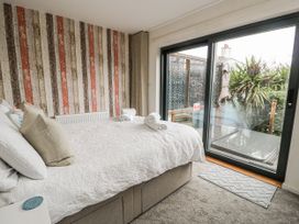 A bedroom with a bed and sliding door leading outside at Daisy Cottage in Benllech
