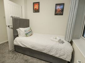 A bedroom with a single bed and wall art at Daisy Cottage in Benllech