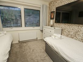 A bedroom with two beds and a dresser at Daisy Cottage Benllech