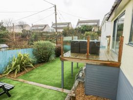 A garden with a deck and hot tub at Daisy Cottage in Benllech
