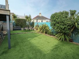 A garden with artificial grass and seating area at Daisy Cottage in Benllech