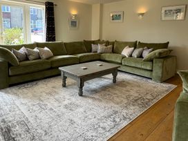 A living room with a green sofa and coffee table at Trevose House in Crantock