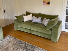 A living room with a green sofa and cushions at Trevose House in Crantock