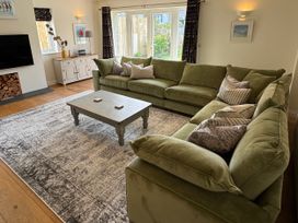 A living room with a green sofa and coffee table at Trevose House in Crantock