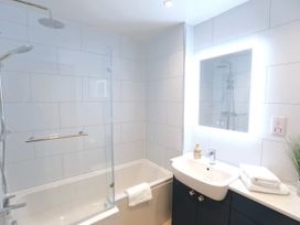 A bathroom with a bathtub, shower, and sink at Honeybee Cottage in Penruddock